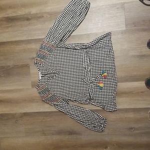 Checkered blouse with intricate details on shoulder and boho belt with pom poms